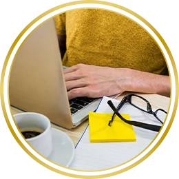Hands using a laptop beside a coffee cup and yellow envelope